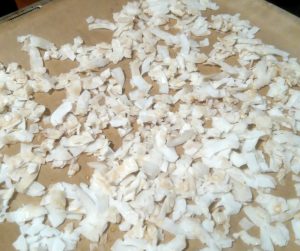 Kokos-Chips backen auf Baclpapier mit Ahornsirup und Meersalz